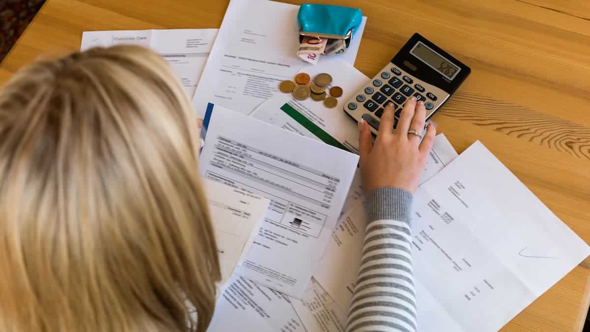 Person using calculator with bills on table
