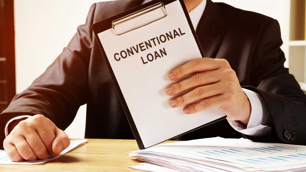 When to Choose Hard Money Over Conventional Financing Person holding a conventional loan document while reviewing financing paperwork at a desk. The image represents When to Choose Hard Money Over Conventional Financing, highlighting a borrower comparing loan options and considering faster, flexible funding for real estate or investment needs.